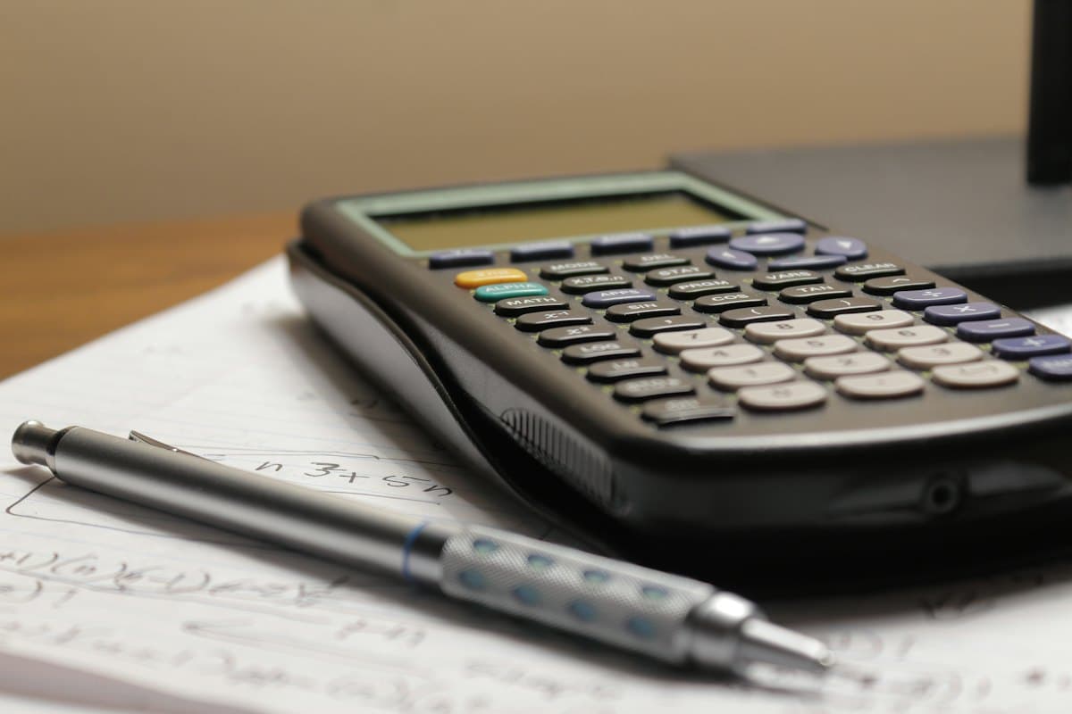 Calculadora i bolígraf sobre uns papers